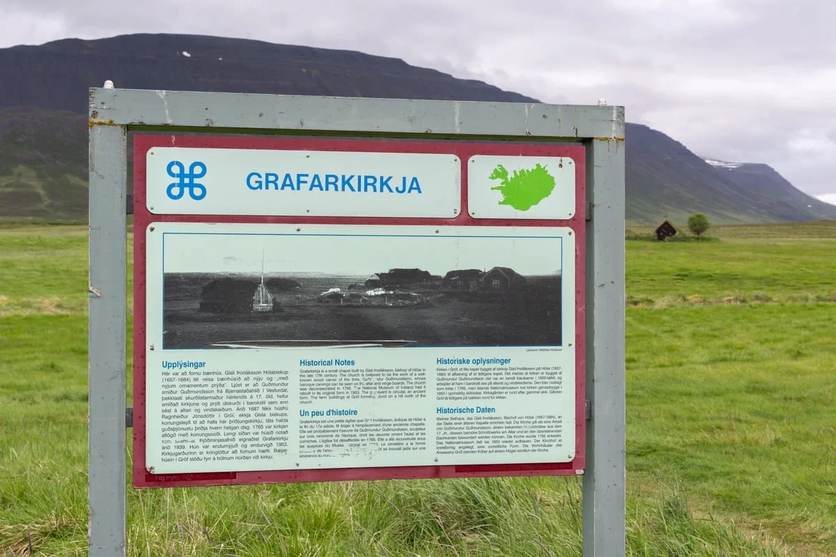 Panneau touristique multilingue devant un paysage de montagne verdoyant