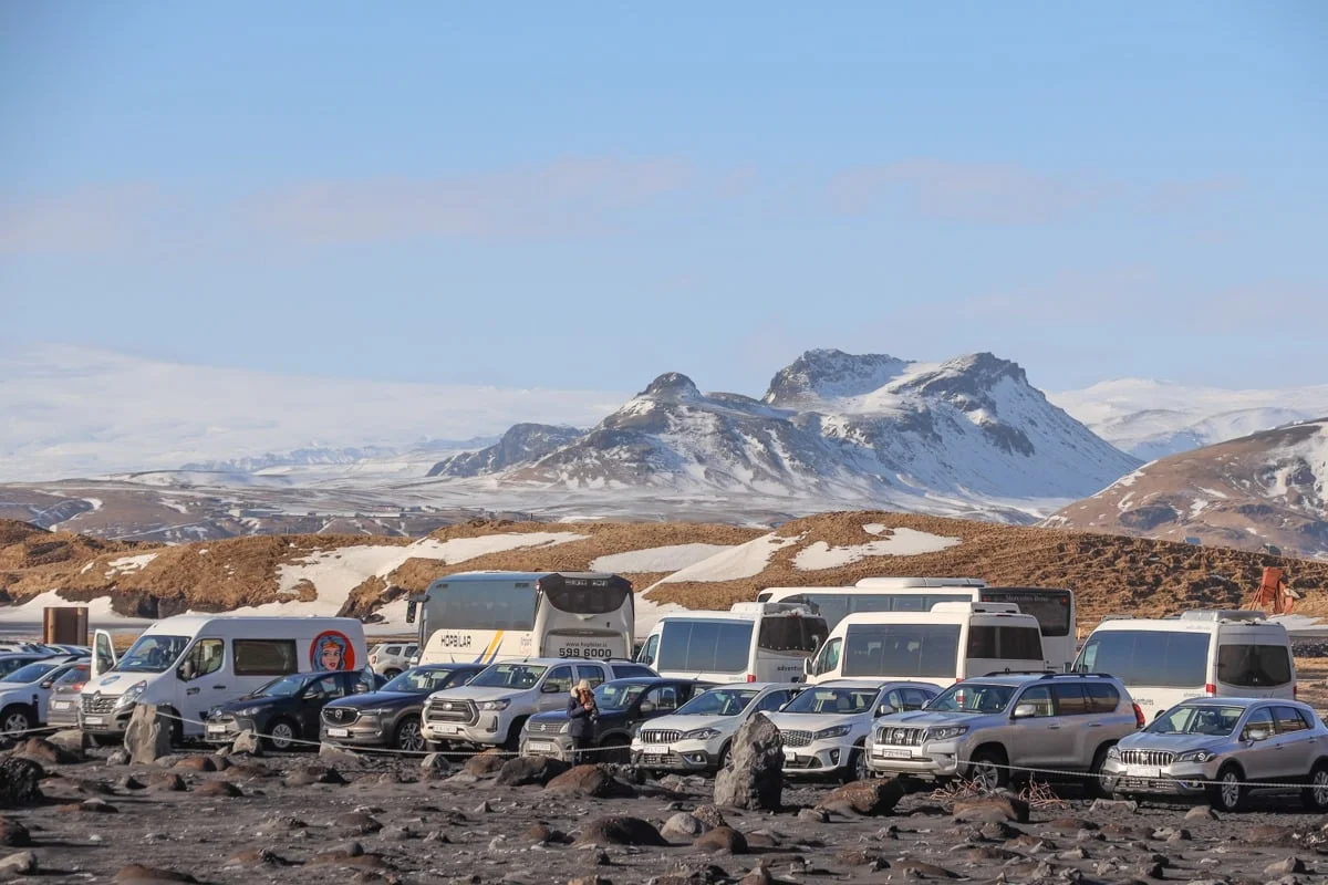 Grand parking de véhicules devant des montagnes enneigées