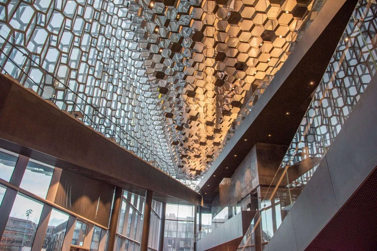 Plafond géométrique hexagonal en verre reflétant une lumière dorée