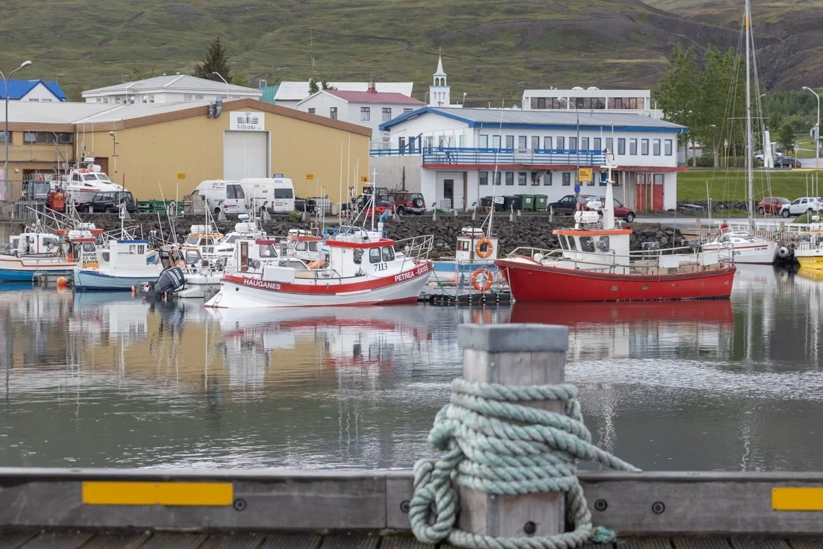 Bateaux de pêche colorés amarrés dans un petit port, reflets sur l'eau