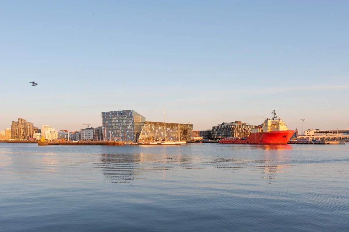 Salle de concert en verre et bateau rouge dans le port au coucher de soleil