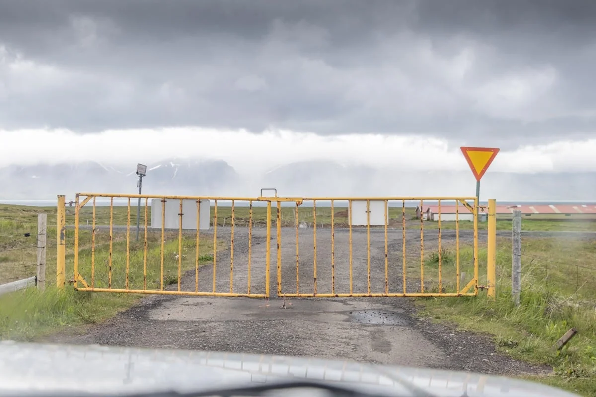 Grand portail métallique jaune fermé sur une piste de graviers