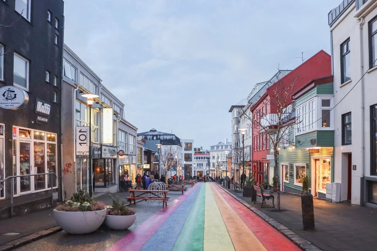 Rue piétonne animée avec sol peint aux couleurs arc-en-ciel et façades colorées