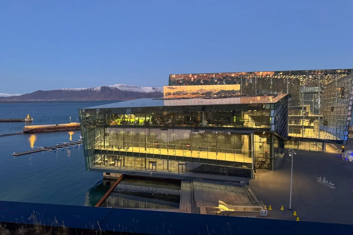 Bâtiment en verre illuminé au crépuscule face à la mer