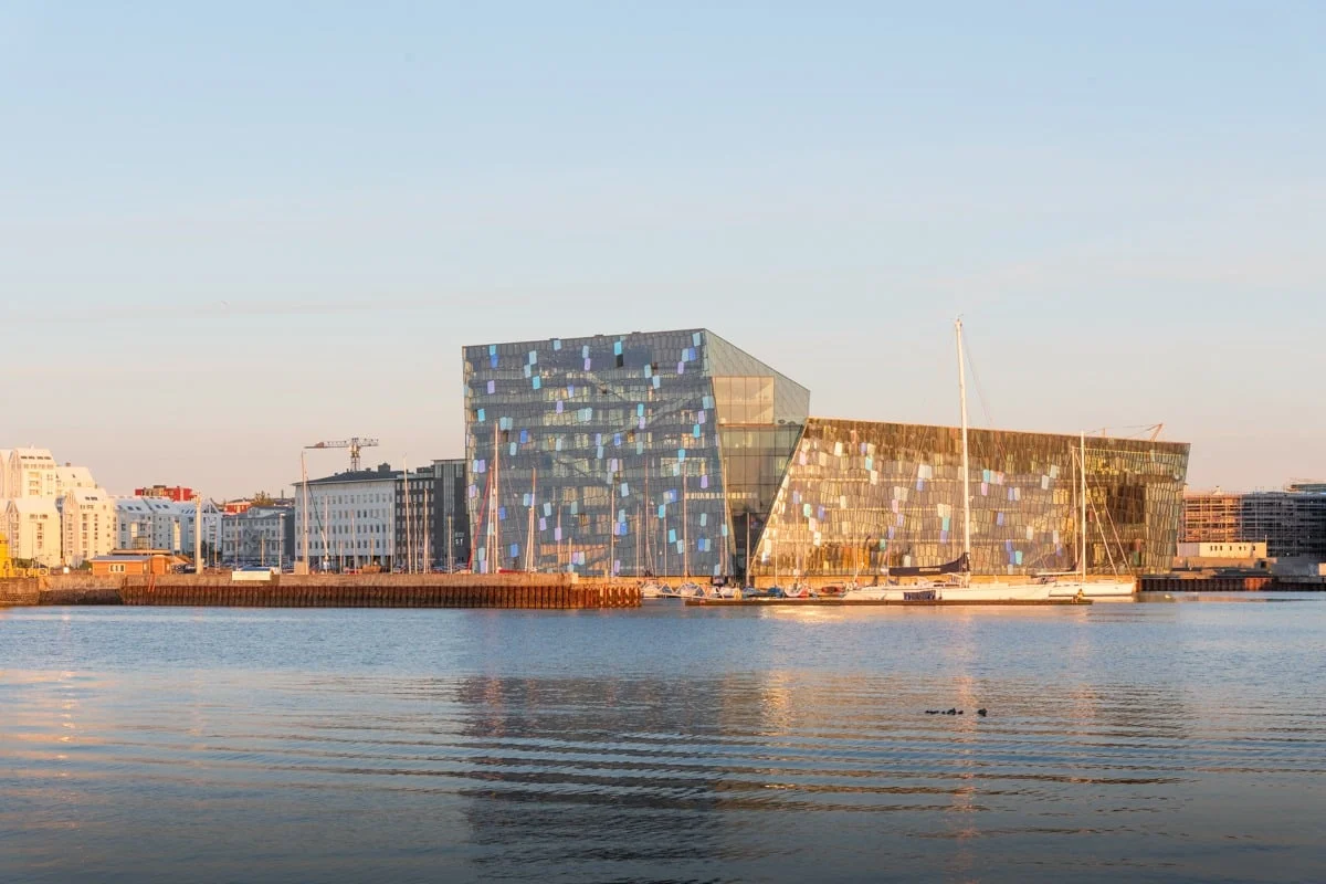 Bâtiment moderne en verre au bord de l'eau, lumière dorée