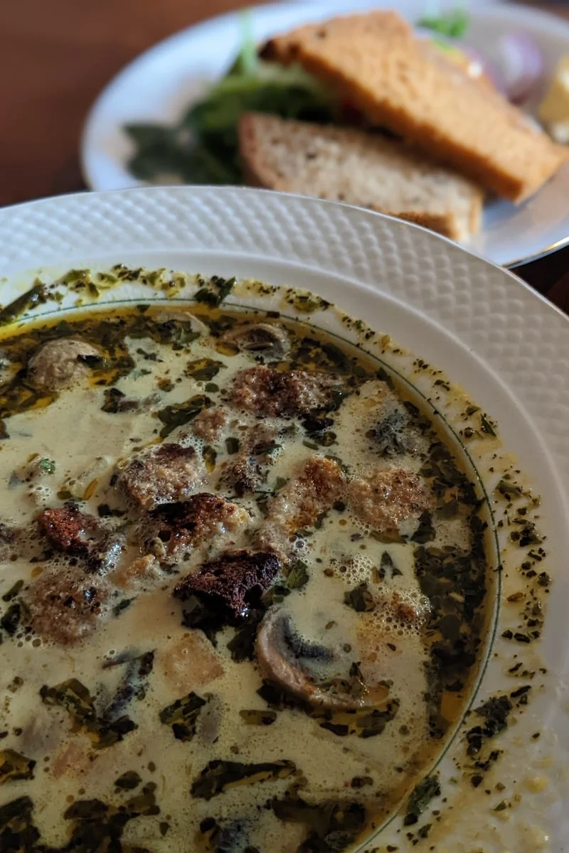 Bol de soupe crémeuse aux champignons et herbes avec pain en arrière-plan