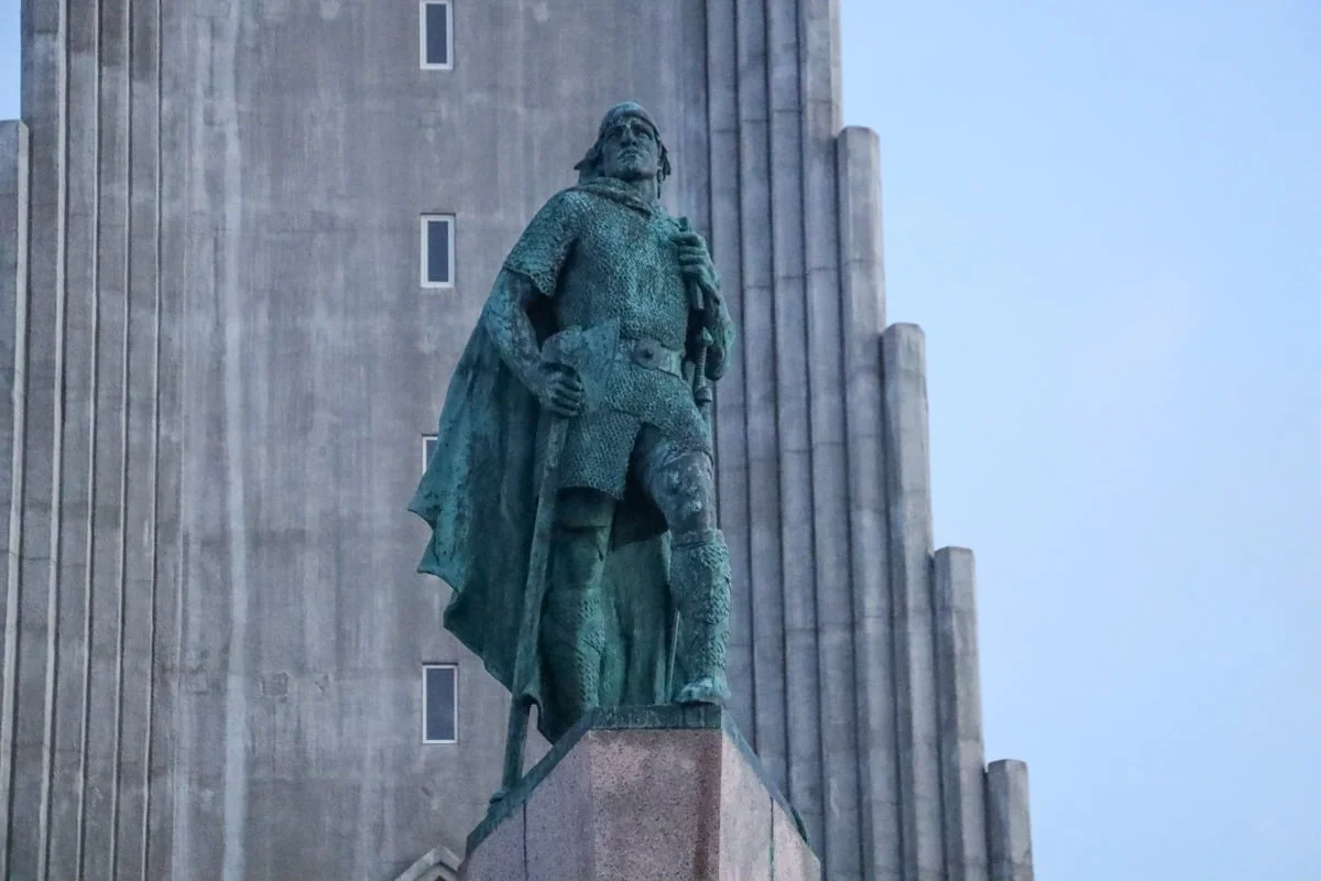 Statue de bronze d'un guerrier viking devant une façade de béton