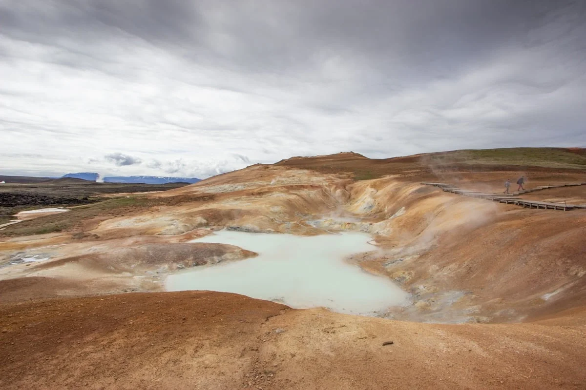 Piscine géothermique laiteuse entourée de terres ocre et de vapeur