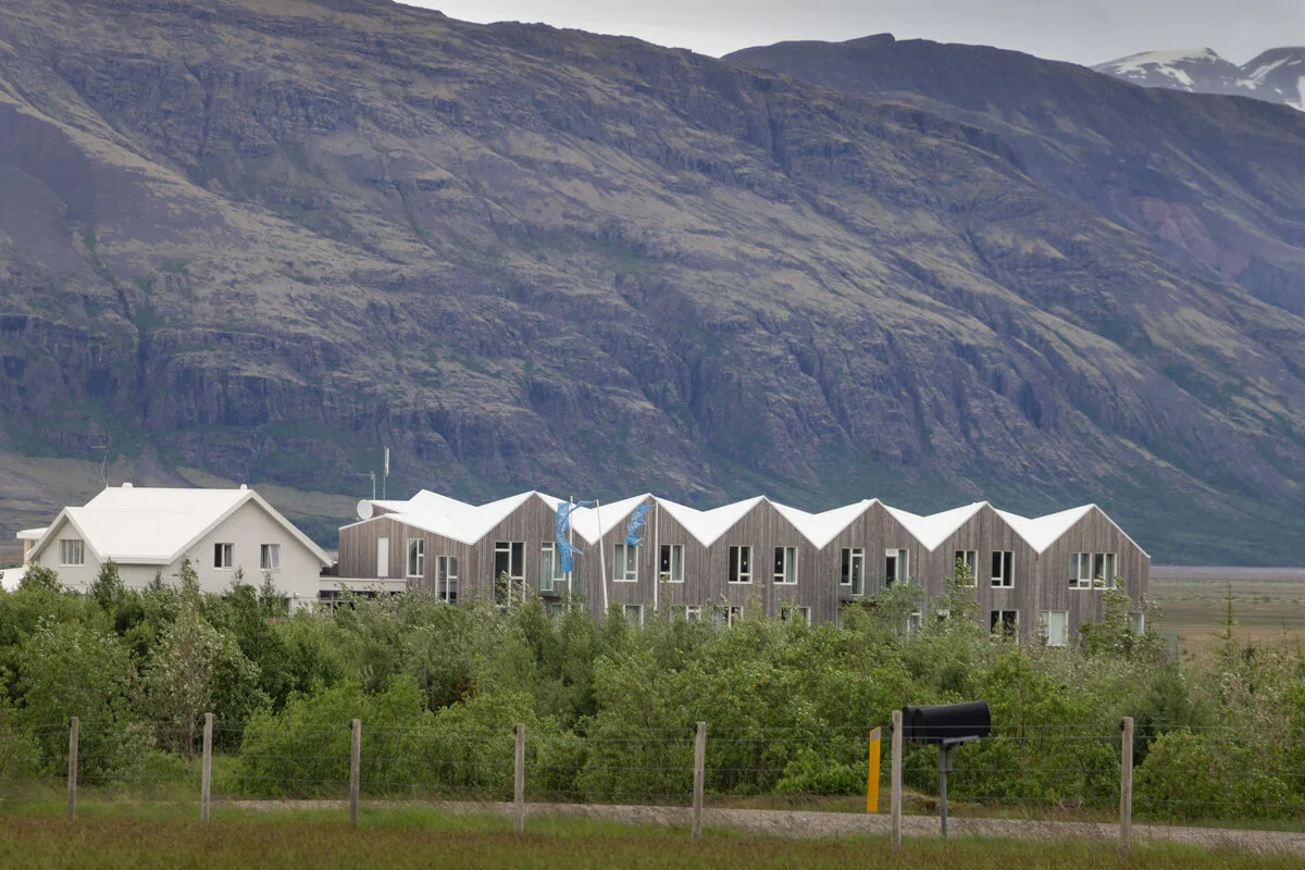 bâtiments alignés du Fosshotel au pied d'une montagne