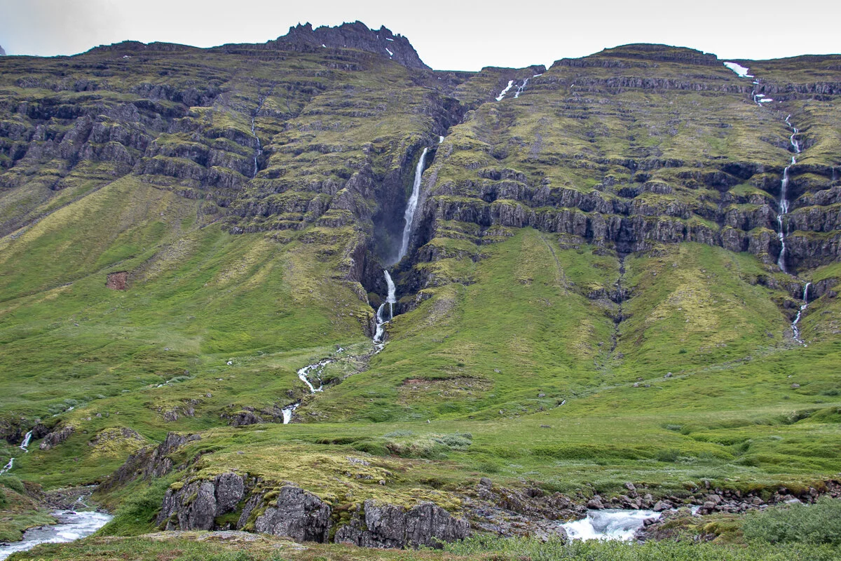 une cascade tombant d'une montagne verdoyante