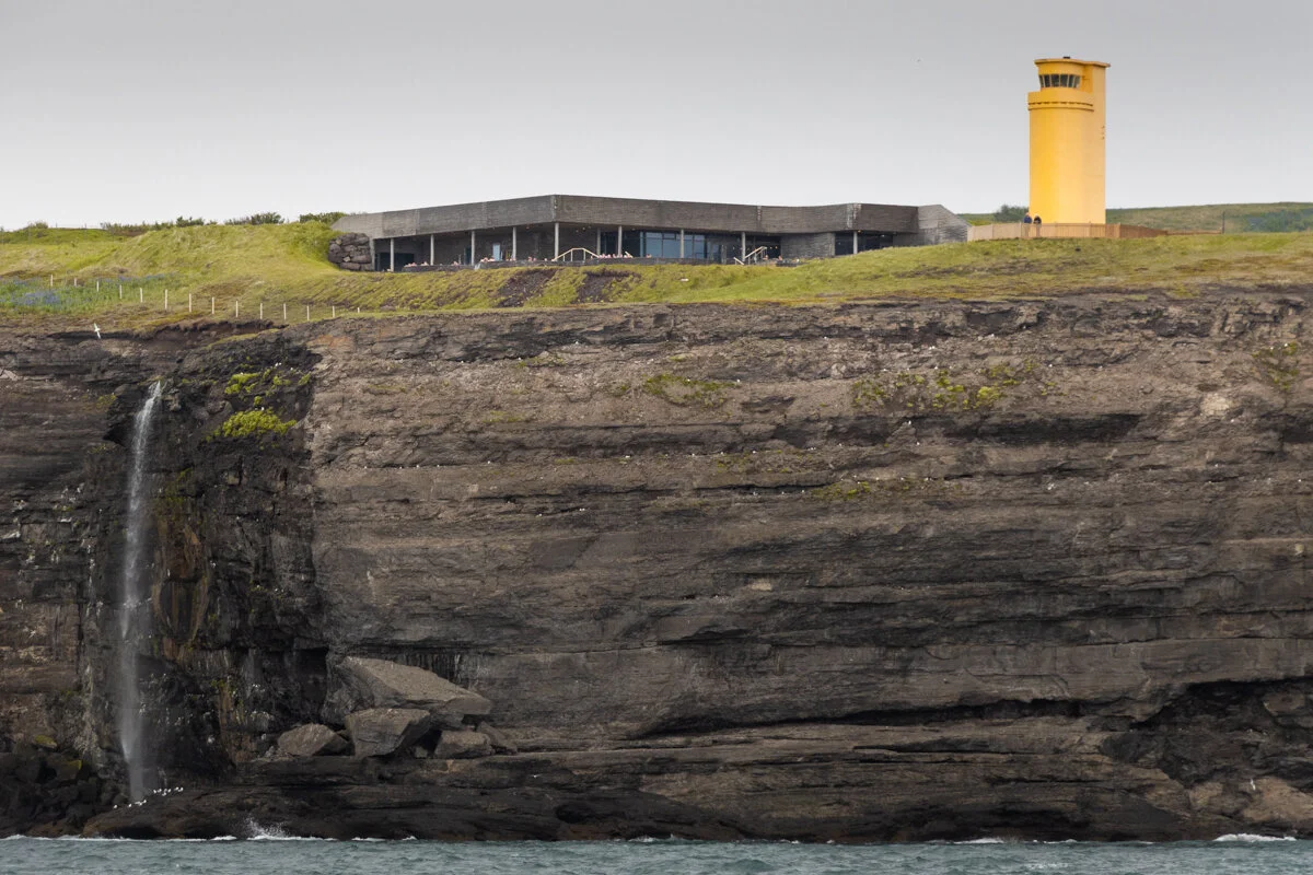 phare jaune sur la falaise avec petit filet d'eau, vu depuis la baie