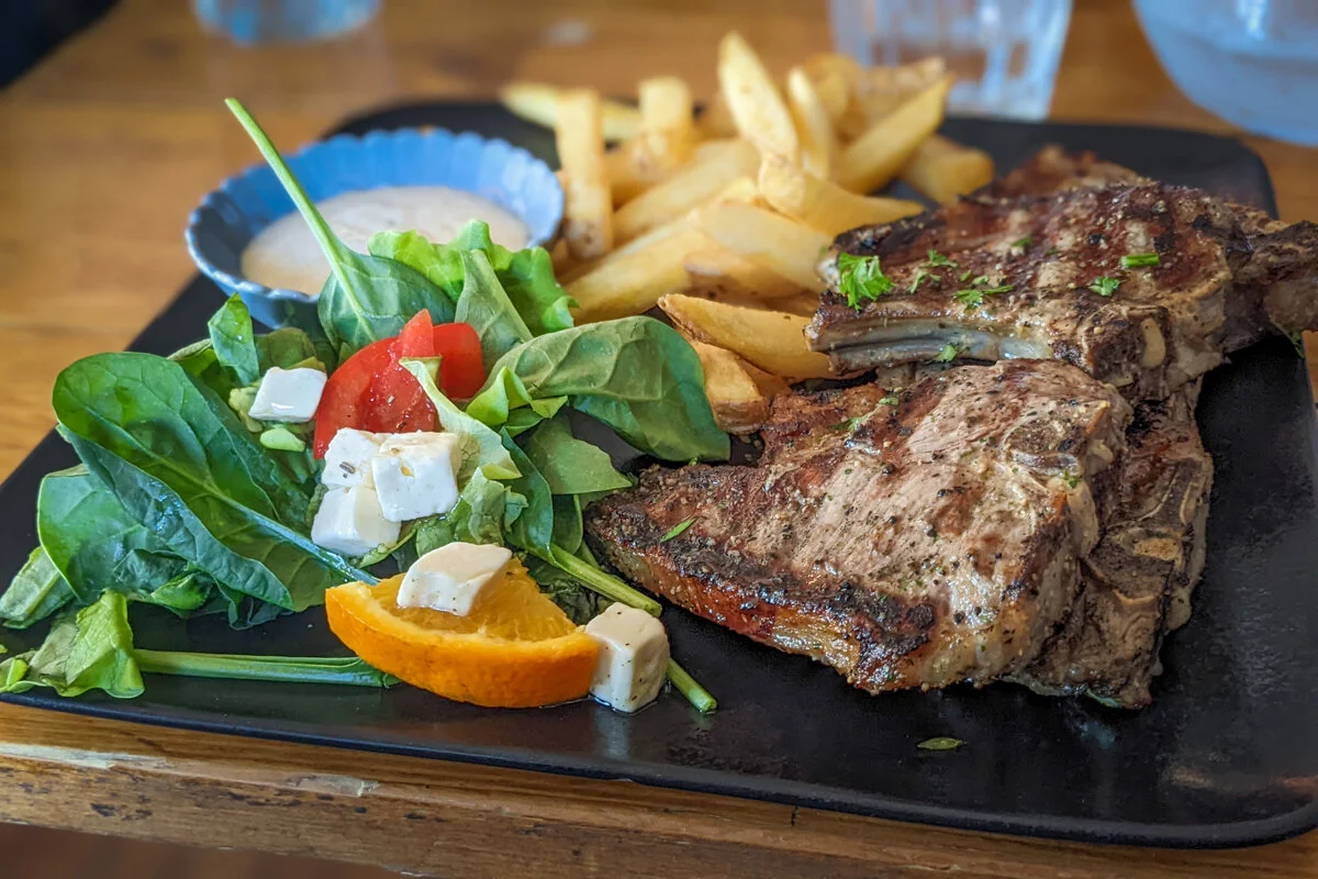 un steak grillé servi avec frites et salade
