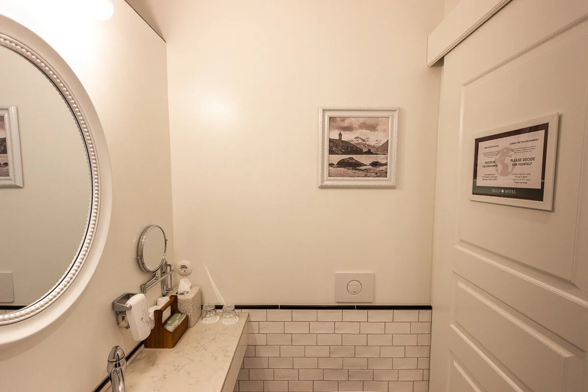 salle de bain avec lavabo, miroir et carrelage blanc