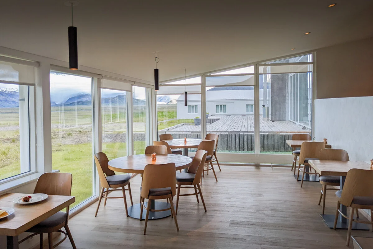 salle avec tables, chaises et grandes baies vitrées dans le restaurant du Fosshotel