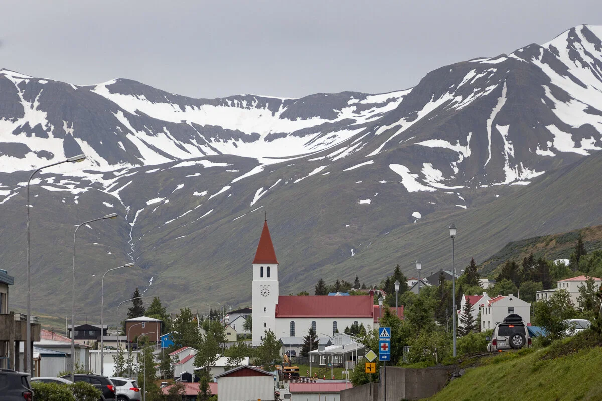 église et maisons de Siglufjordur au pied de montagnes enneigées