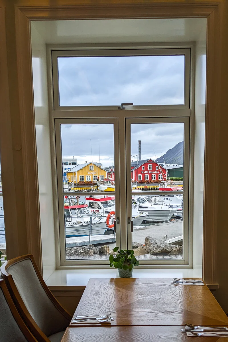 vue d'un port avec des bâtisses colorées à travers une fenêtre du restaurant
