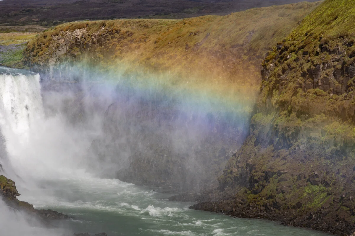une cascade qui crée un arc-en-ciel dans ses embruns
