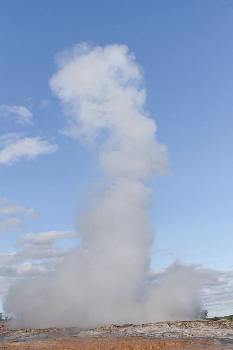 un geyser projette une colonne d'eau et de vapeur vers le ciel