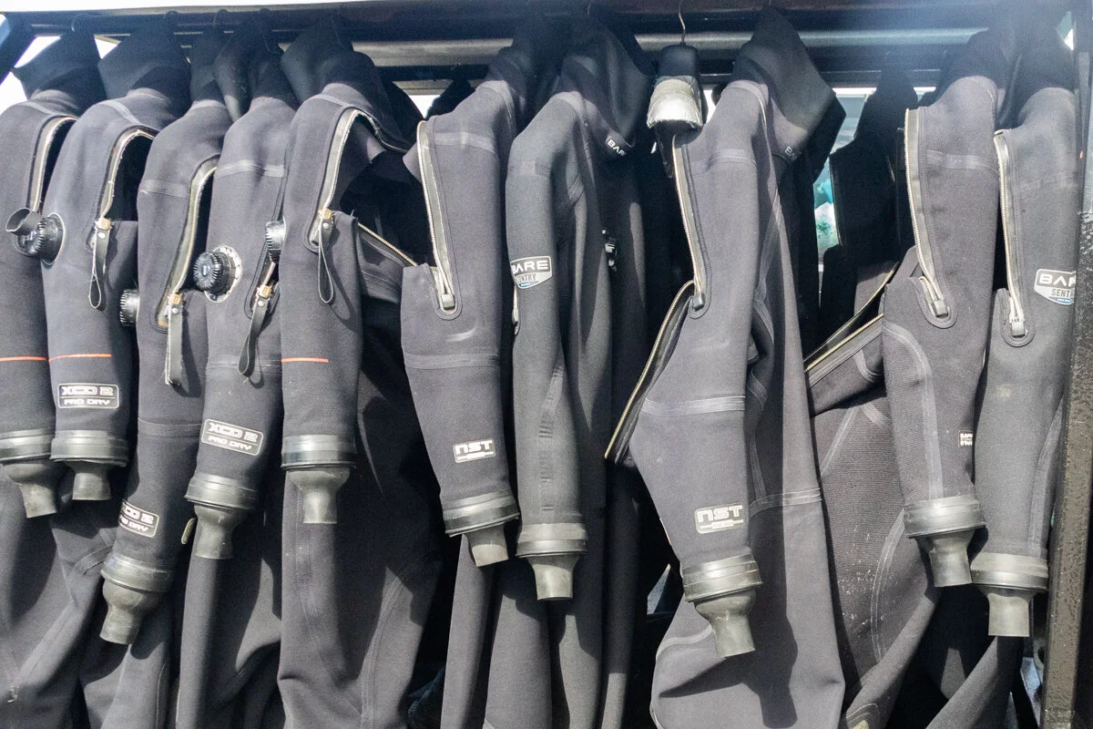 des combinaisons de plongée suspendues sur des cintres
