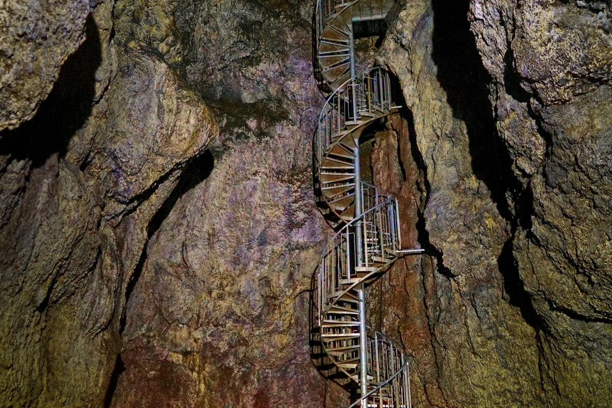 un escalier métallique s'élève entre deux parois rocheuses