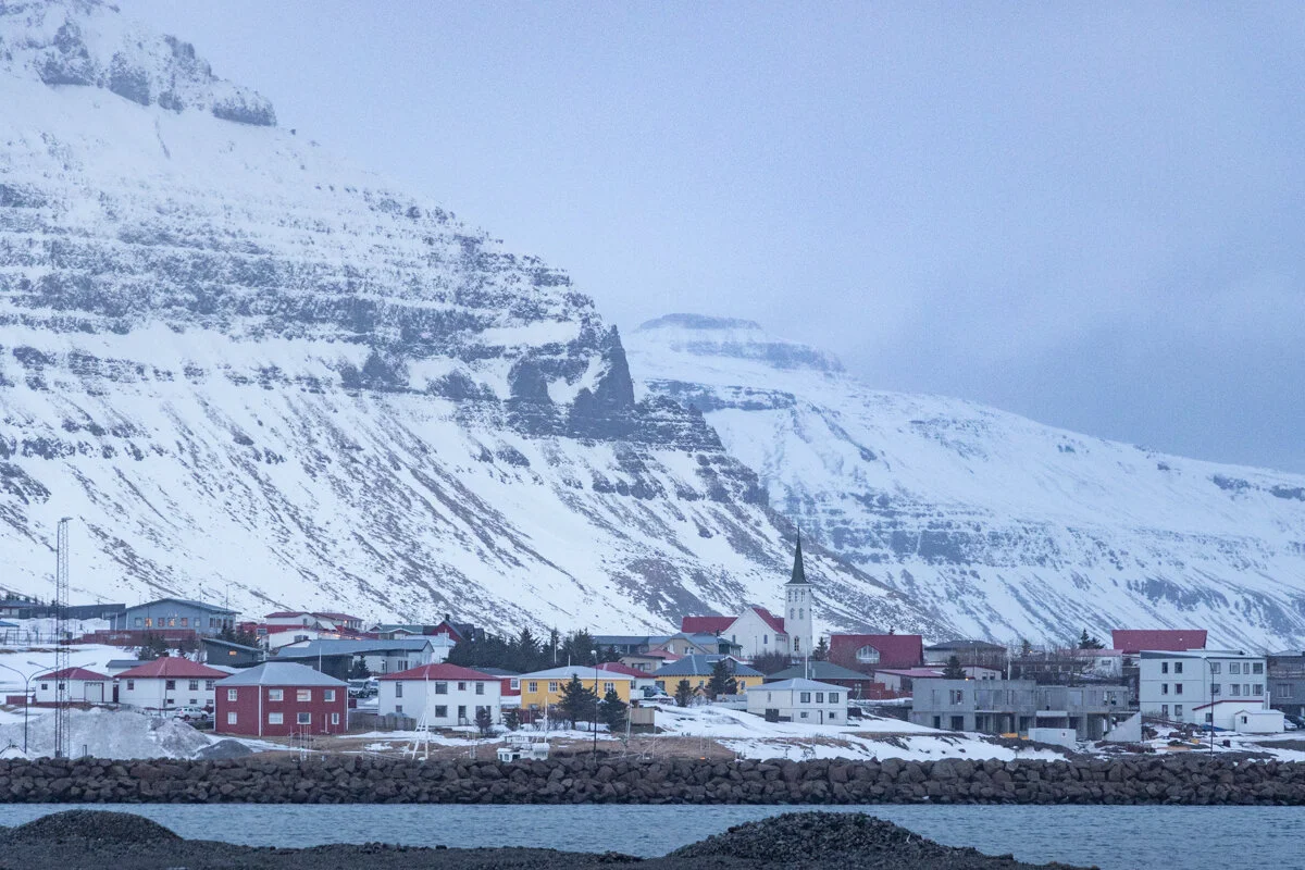 village côtier aux maisons colorées au pied d'une montagne enneigée