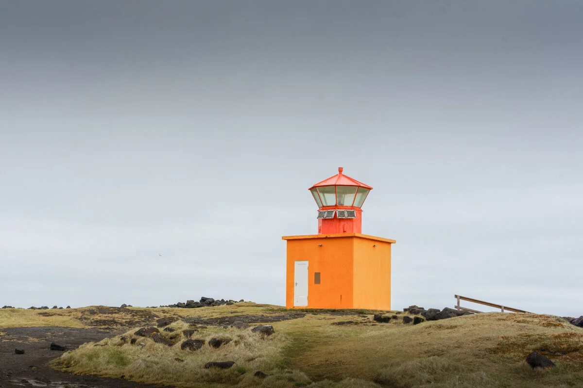 phare orange et rouge sur un terrain herbeux
