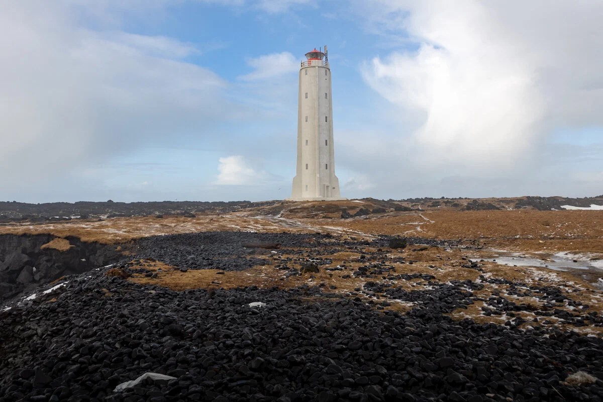 un phare blanc sur un terrain volcanique noir et rocheux