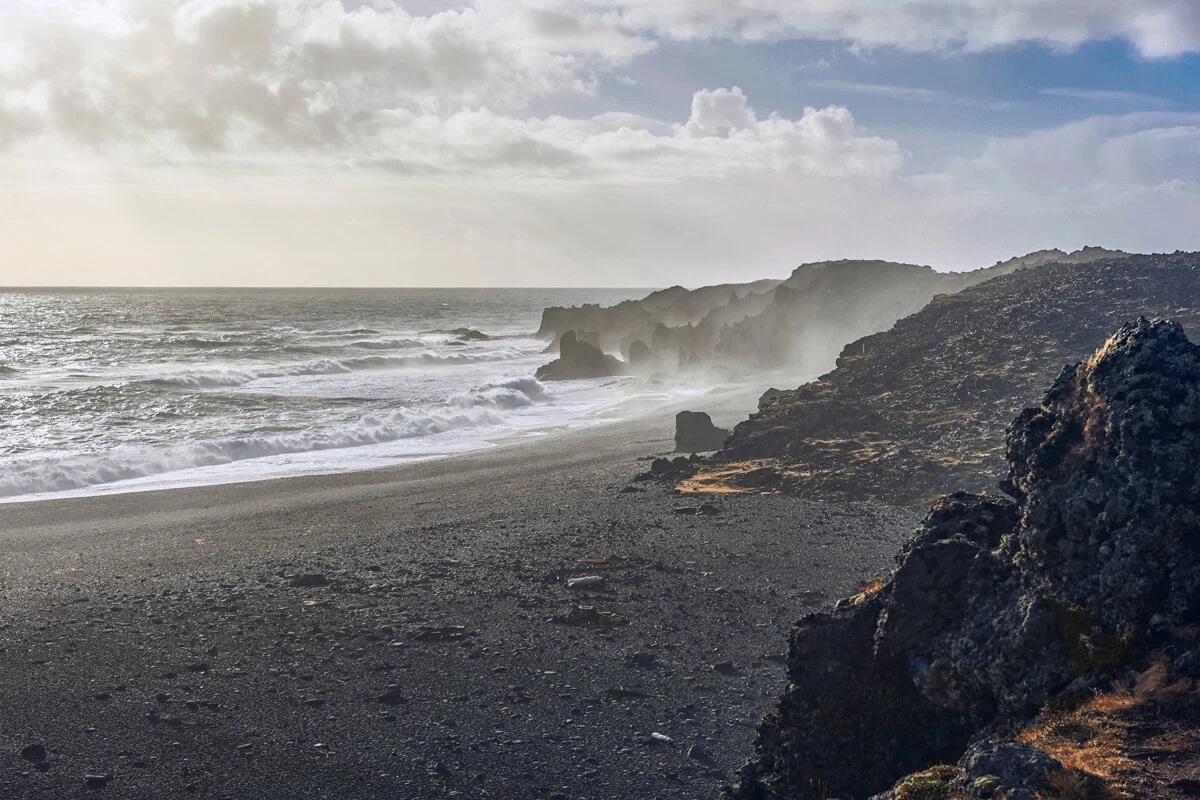 plage de sable noir avec vagues et falaises rocheuses