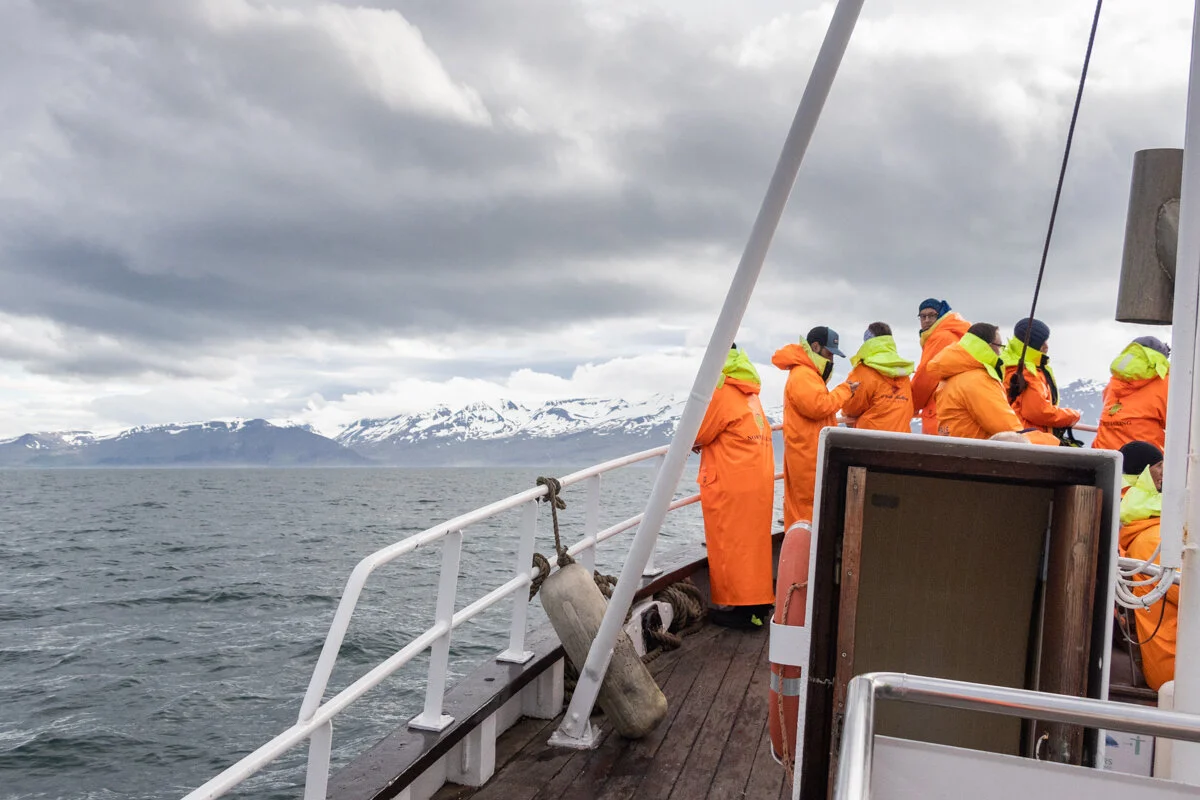 des personnes en gilets de sauvetage orange sur un bateau en mer