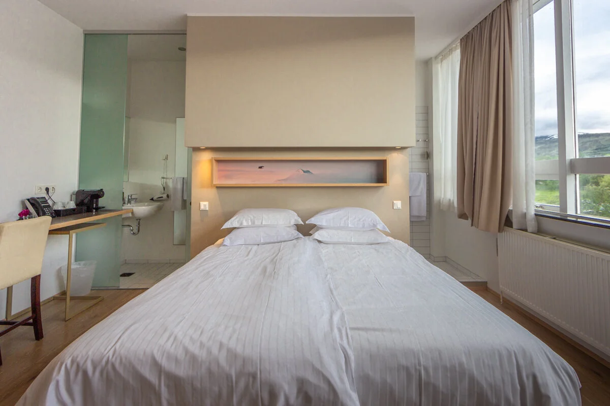 chambre avec lit double blanc et tête de lit éclairée