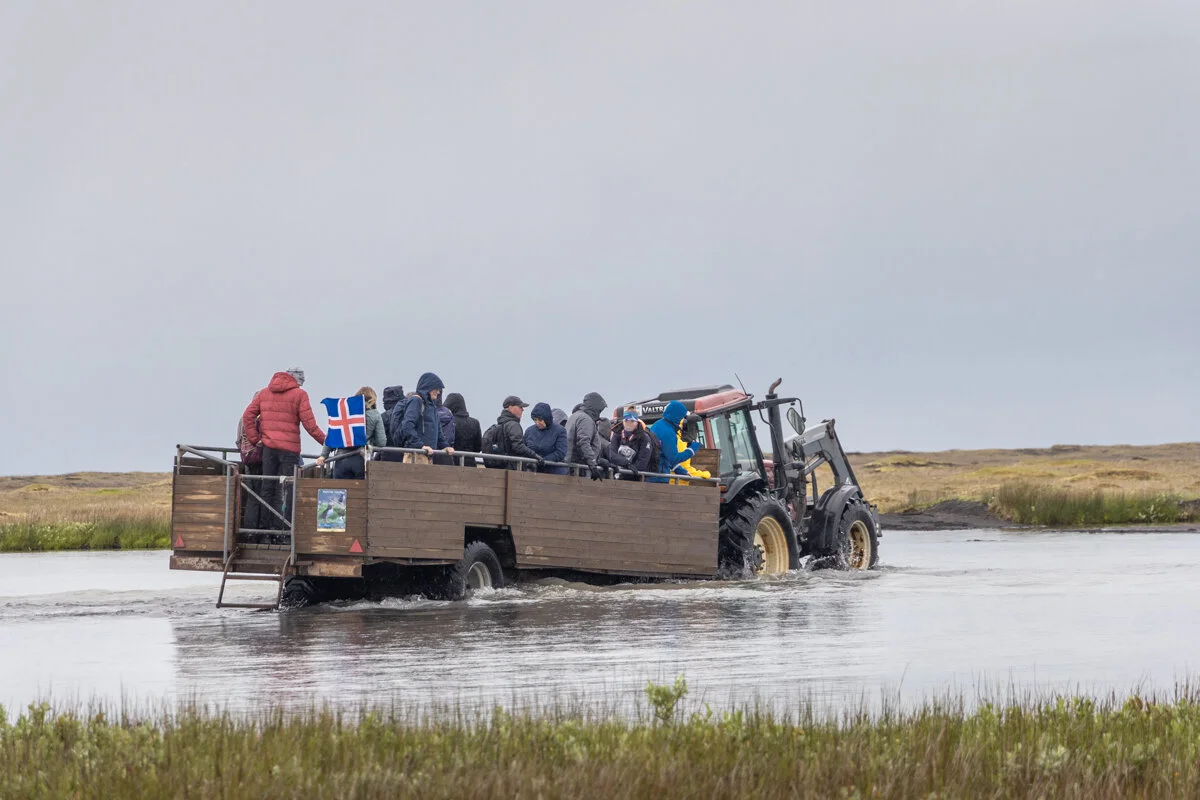 un tracteur tire une barge chargée de touristes sur de l'eau
