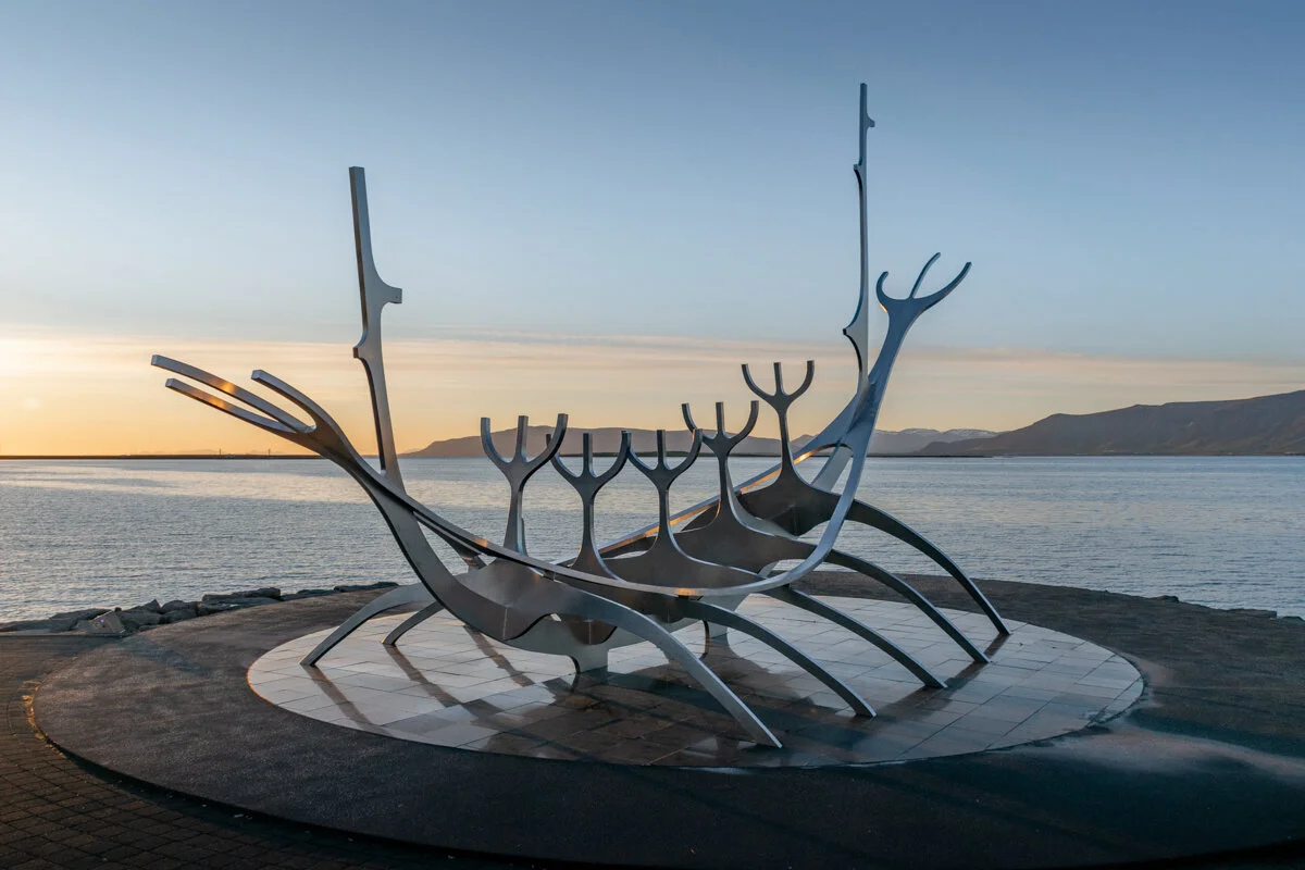 sculpture métallique en forme de bateau de viking au bord d'eau au coucher du soleil