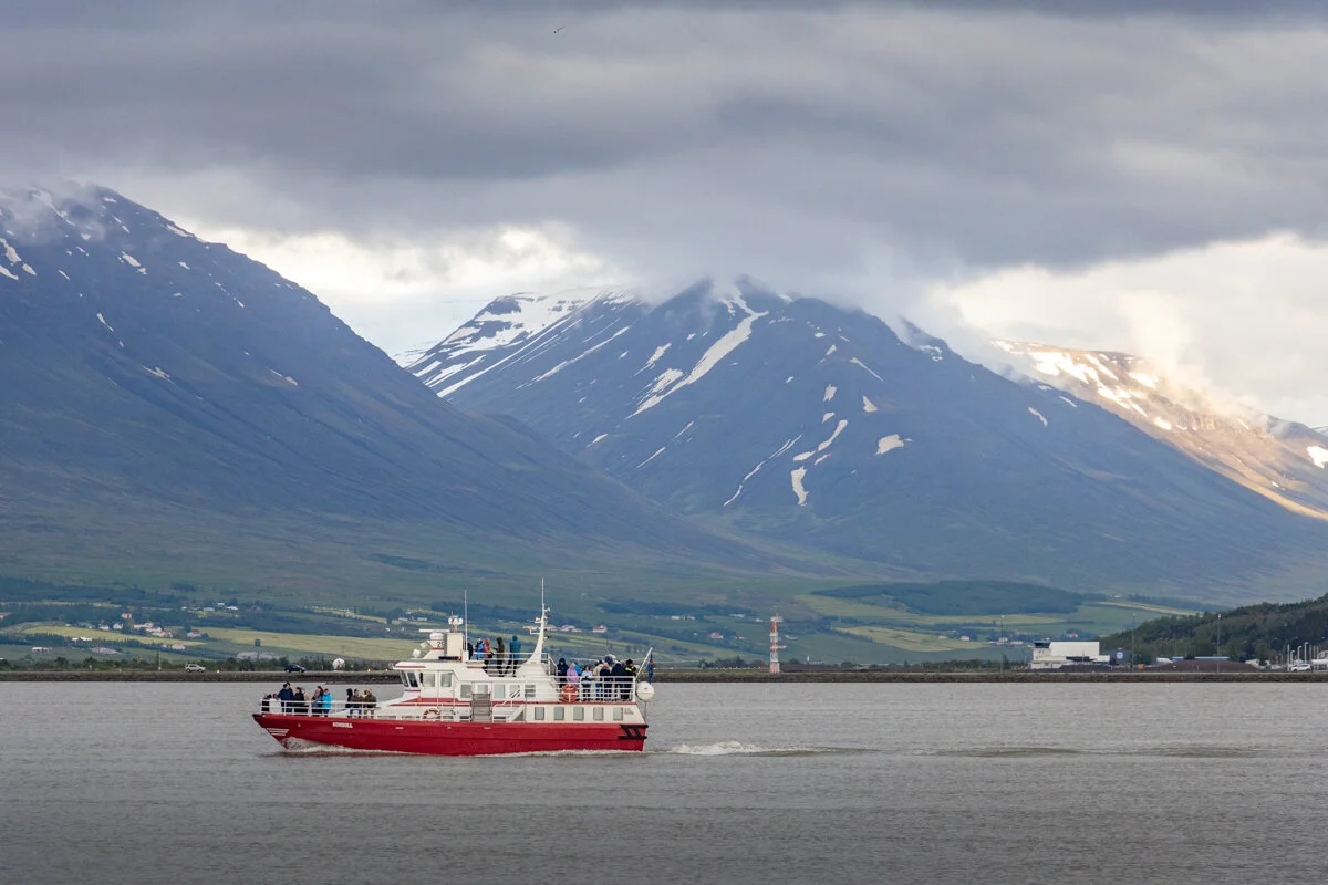 bateau rouge dans une baie avec montagne enneigée en arrière-plan