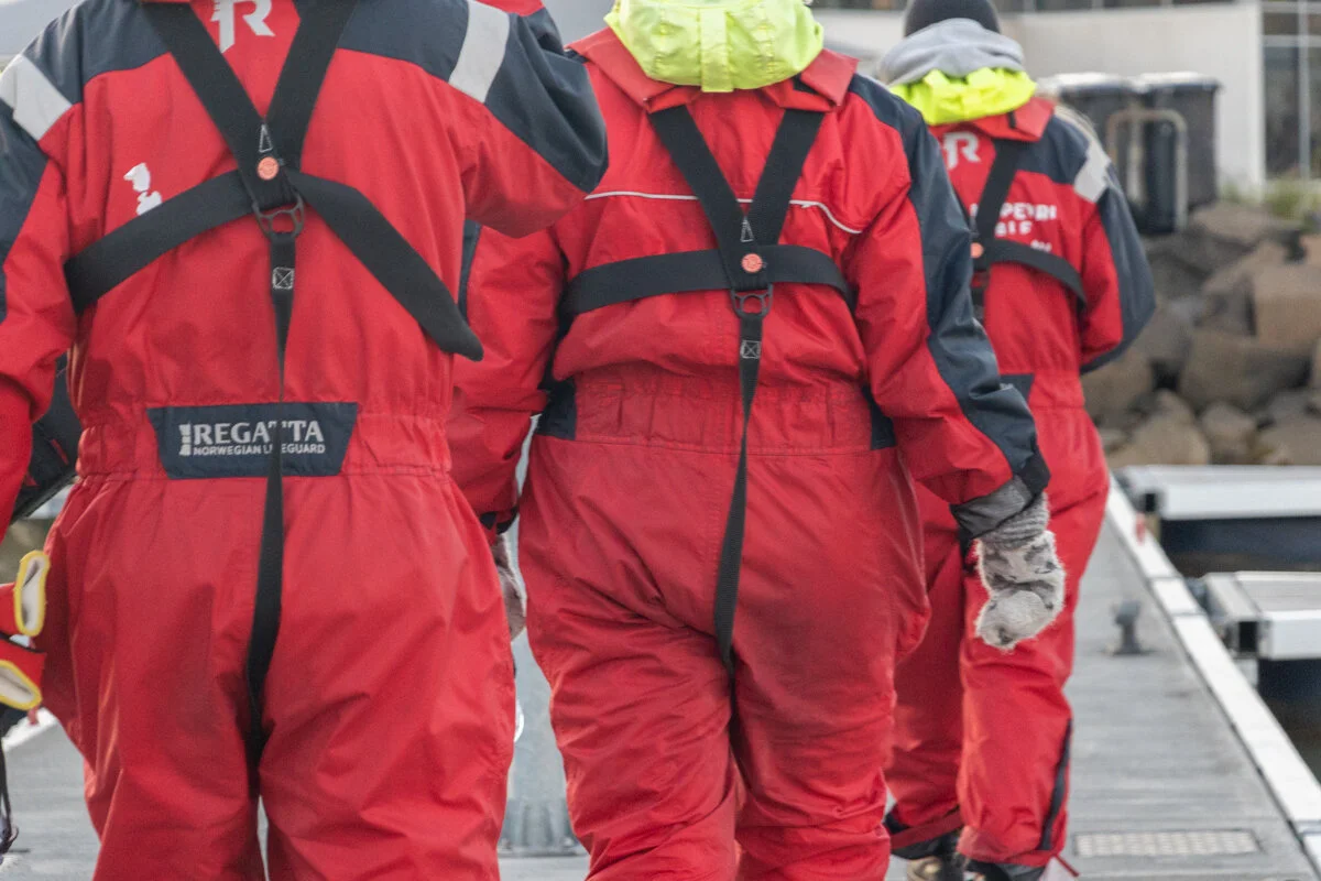 personnes en combinaison rouge qui marchent sur un ponton