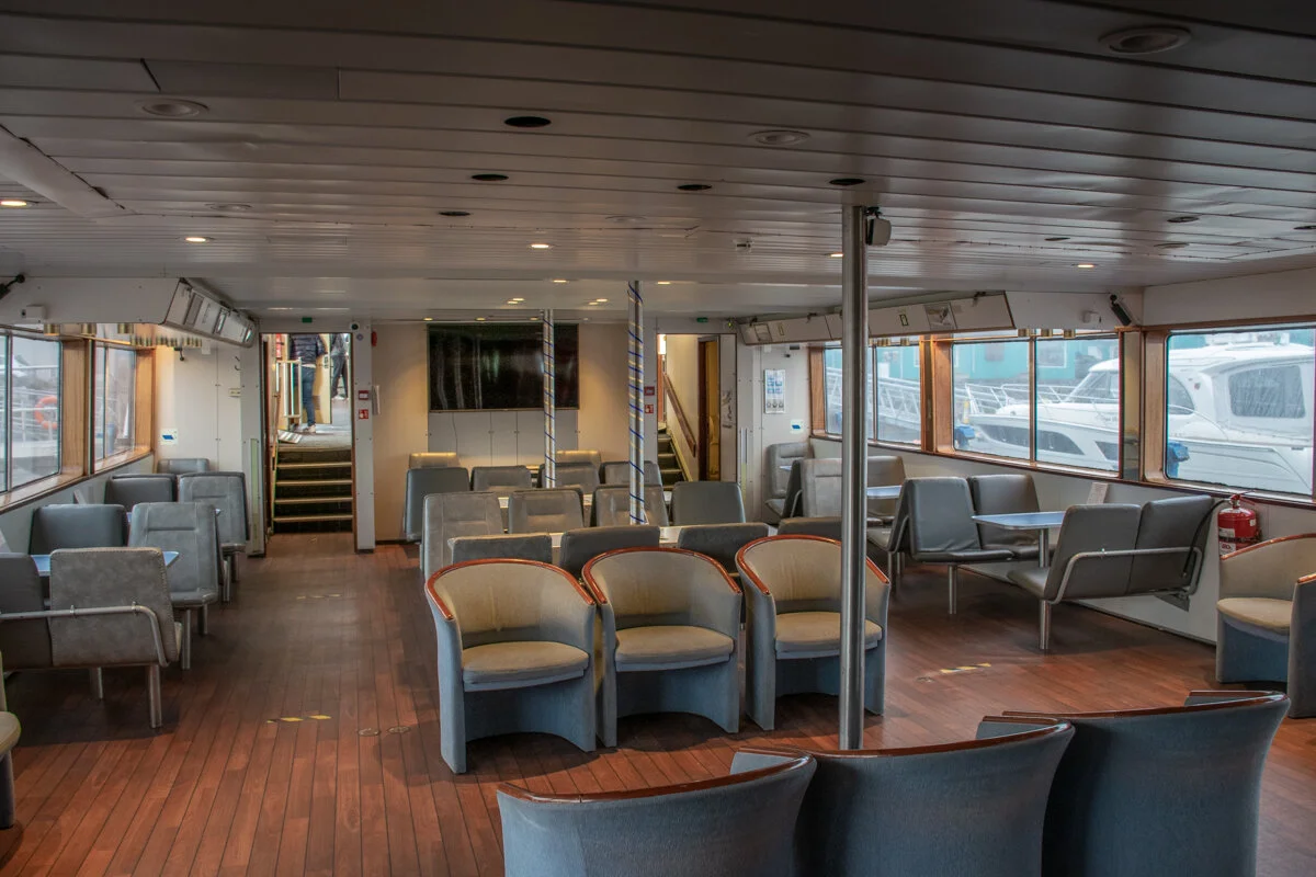 intérieur d'un bateau avec salon, chaises et grandes fenêtres
