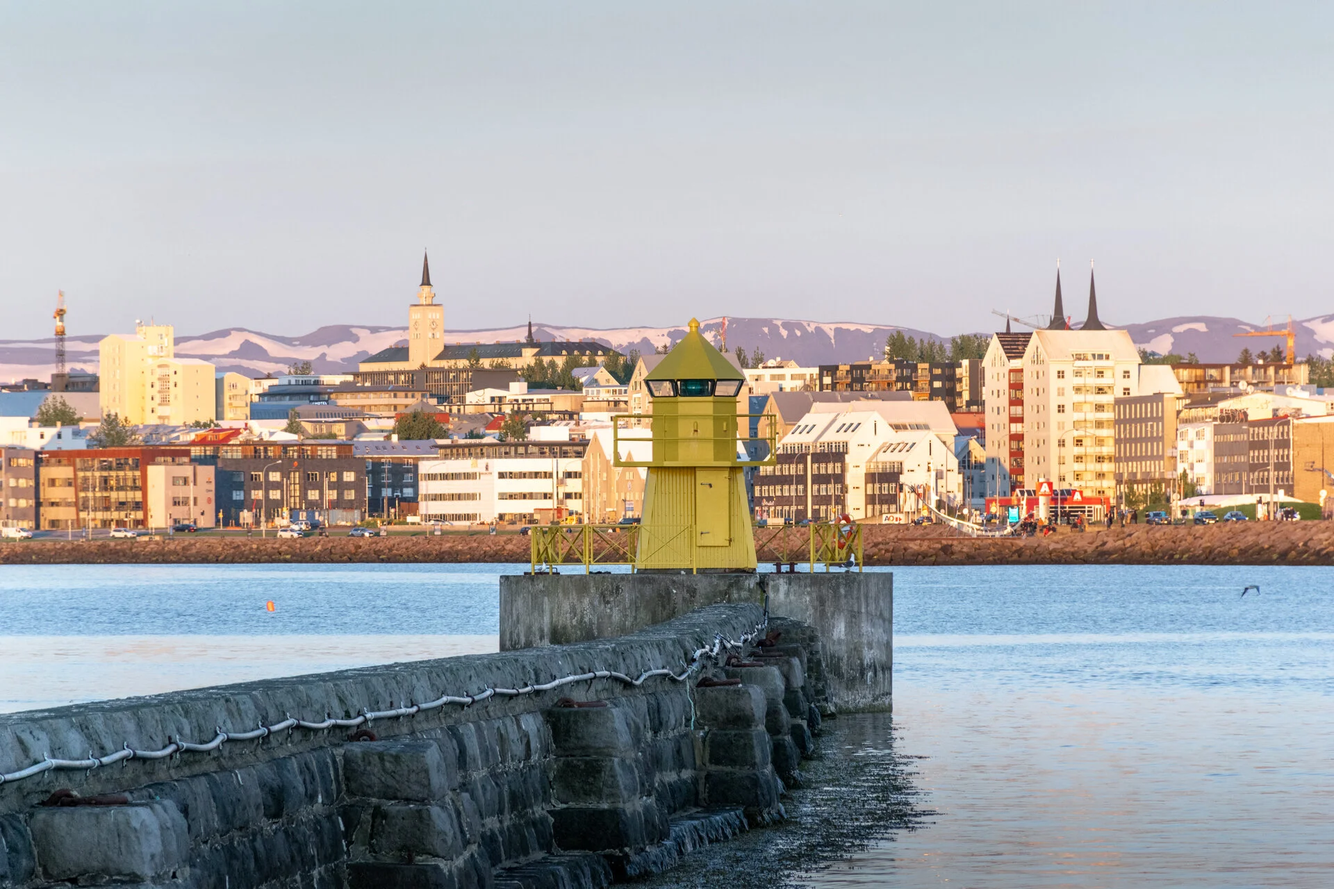 phare jaune sur une jetée face à Reykjavik