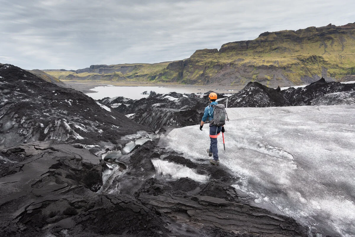 un randonneur sur la glace du Solheimajokull avec de la roche noire