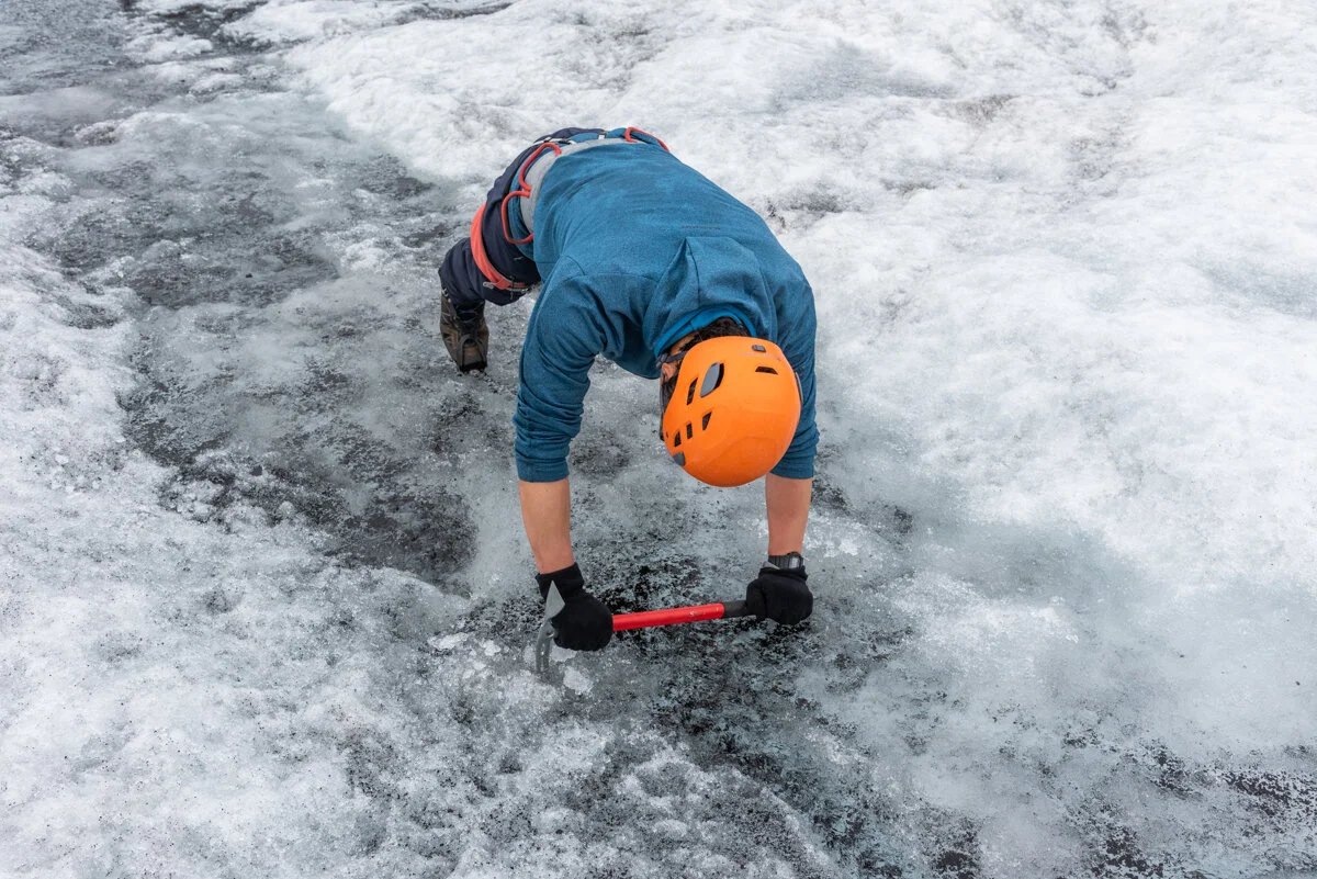 personne avec casque et piolet qui se tient sur la glace