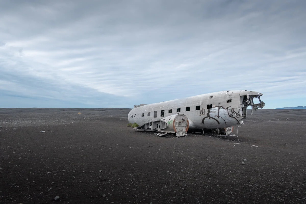 épave d'avion abandonnée sur une plage de sable noir