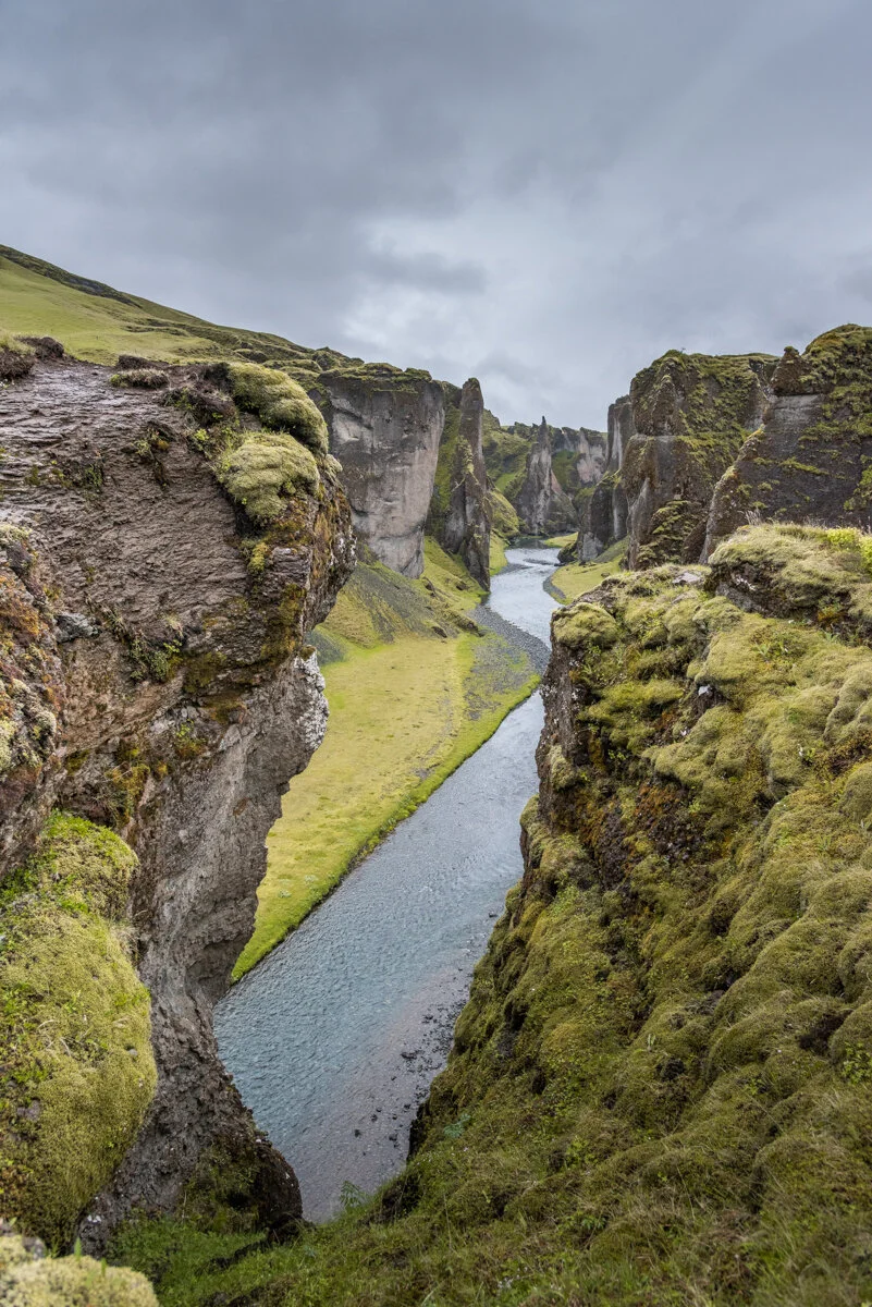 un canyon étroit avec un cours d'eau et des parois rocheuses recouvertes de mousse