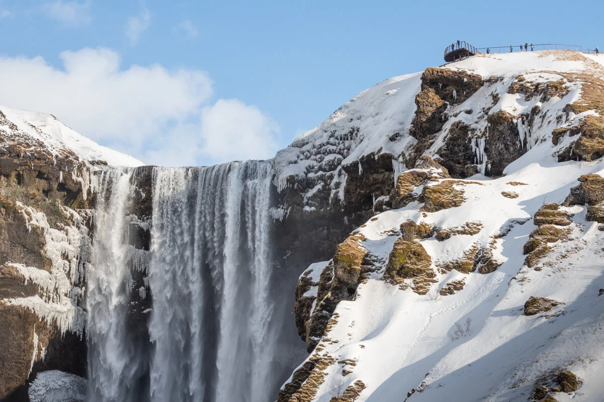 cascade d'eau gelée descendant d'une falaise rocheuse enneigée
