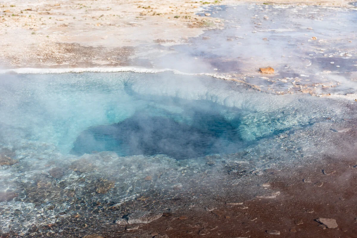 source thermale bleu turquoise entourée de minéraux colorés