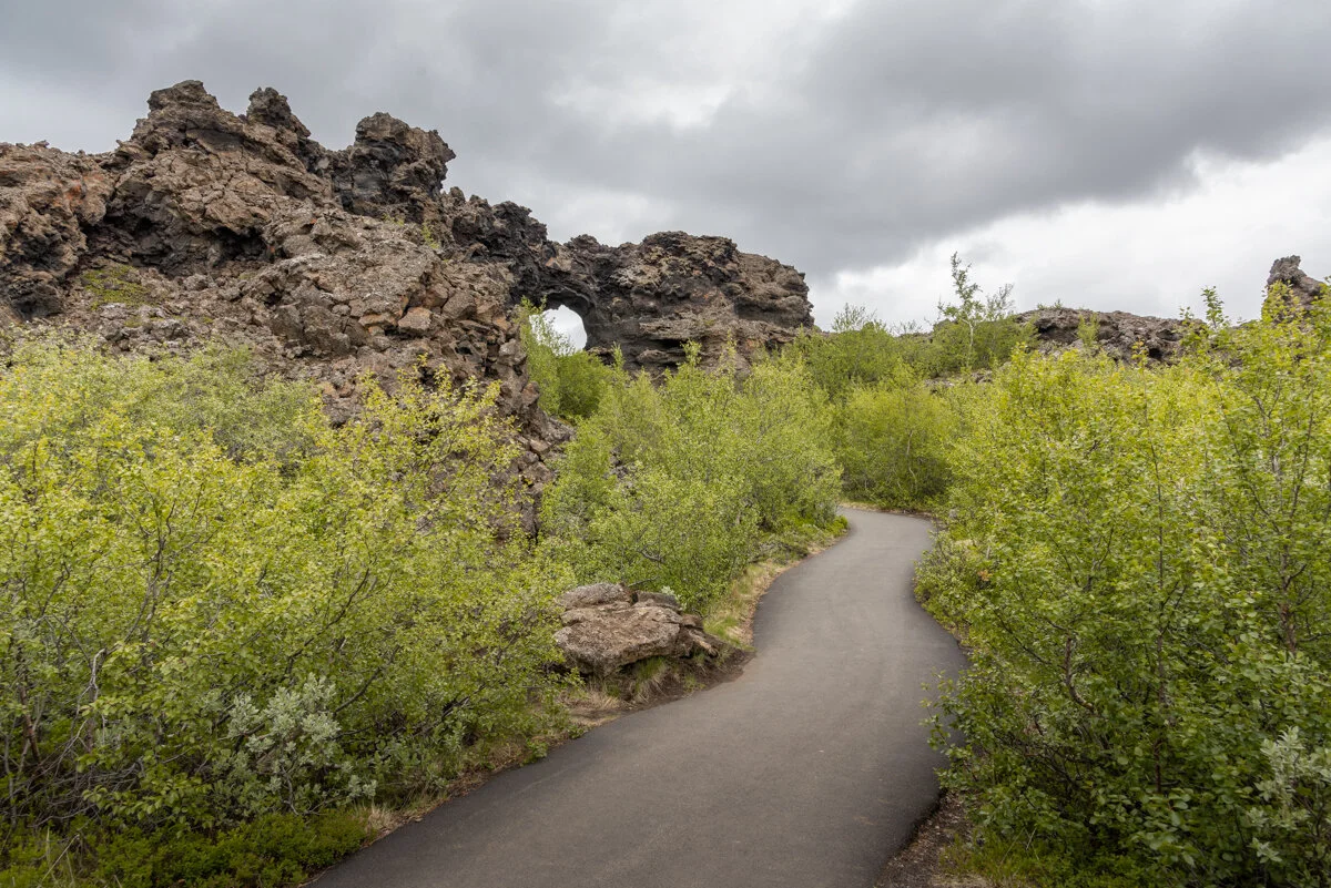 un chemin traverse une végétation dense près de roches volcaniques