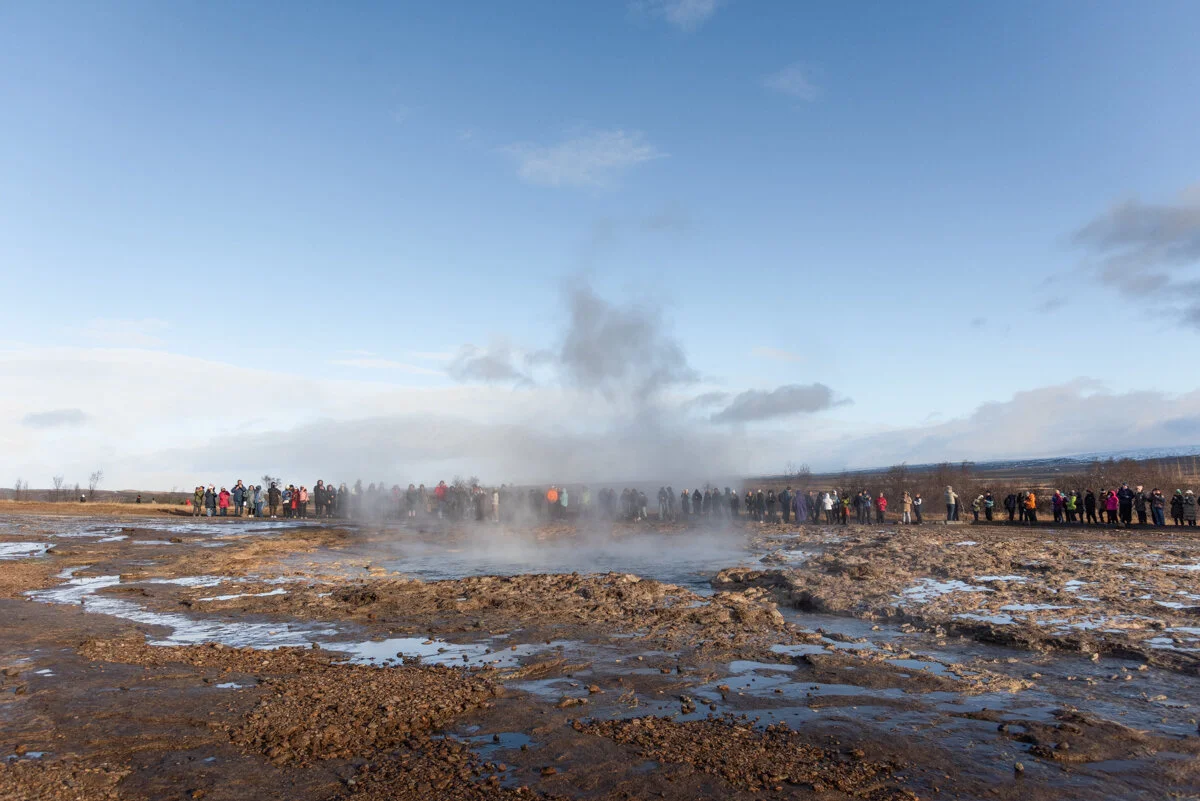 geyser en éruption avec vapeur et visiteurs