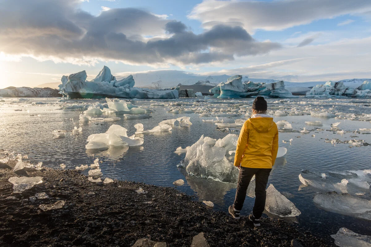 personne en veste jaune face à des icebergs flottants