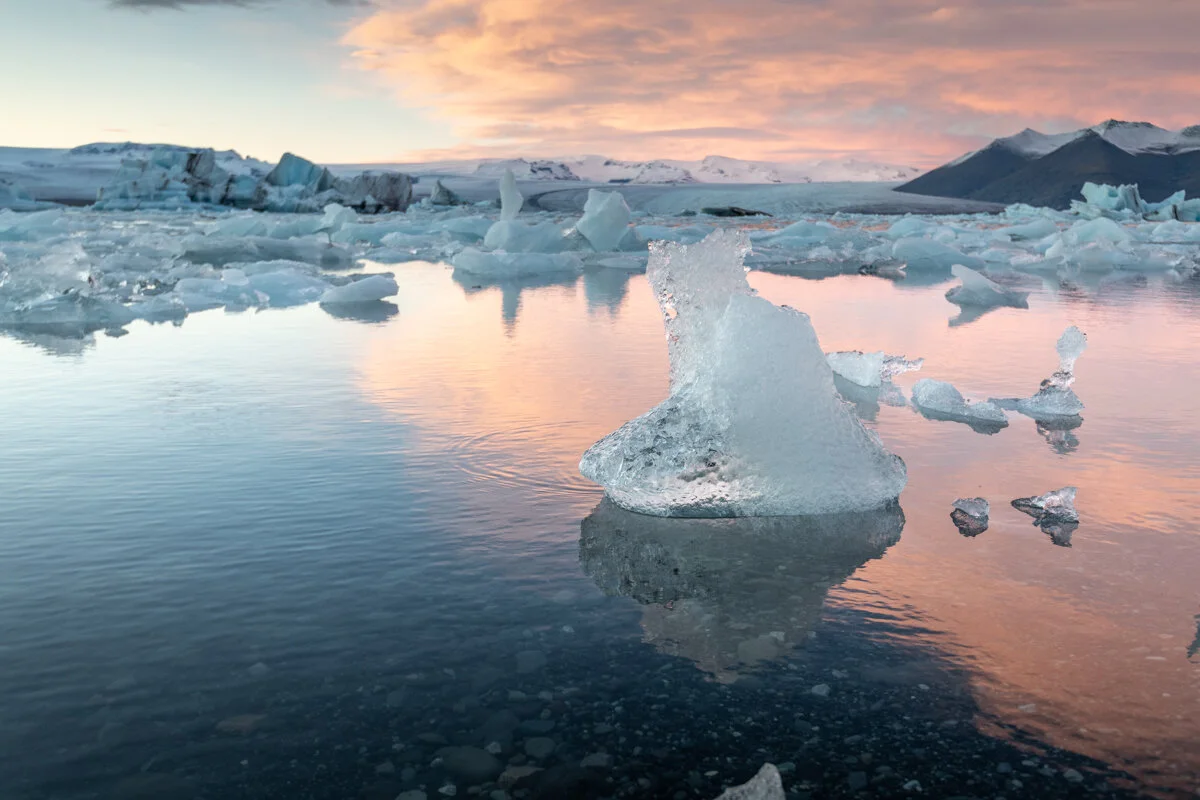 icebergs flottant dans une lagune glaciaire, avec ciel rougeâtre