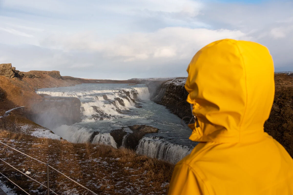 une personne en ciré jaune qui regarde Gullfoss