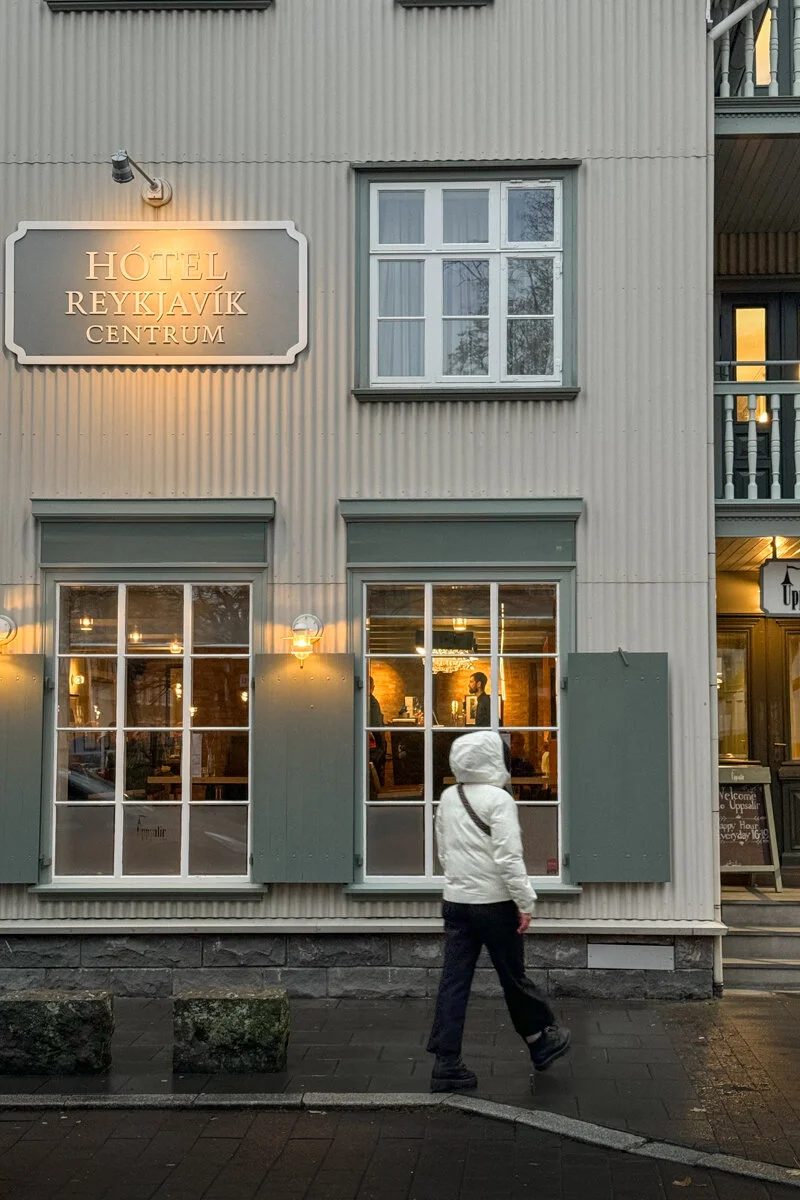 une personne qui marche devant une façade d'hôtel
