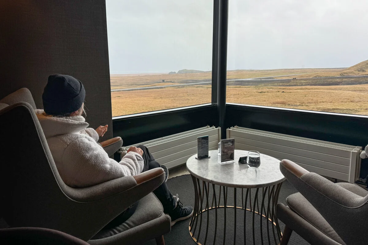 une personne assise face à une baie vitrée surplombant le paysage