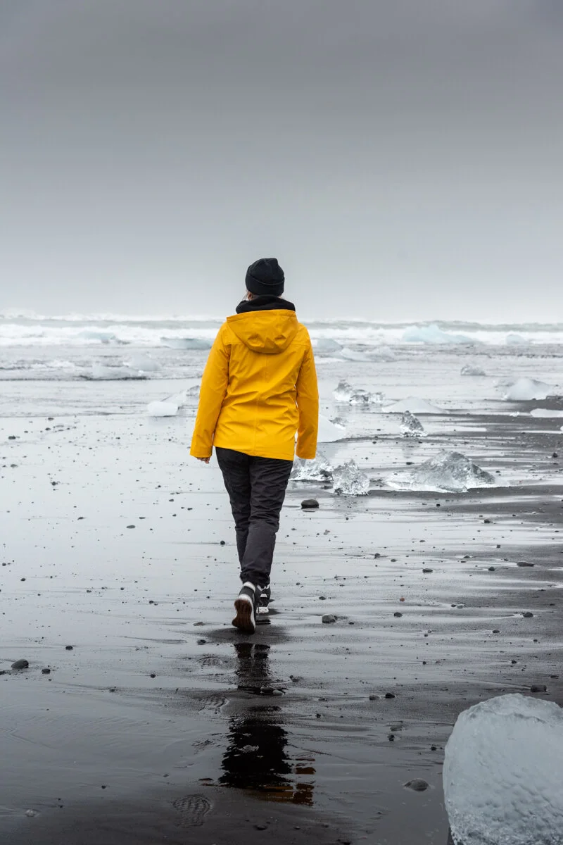 personne en veste jaune qui marche au bord de l'eau